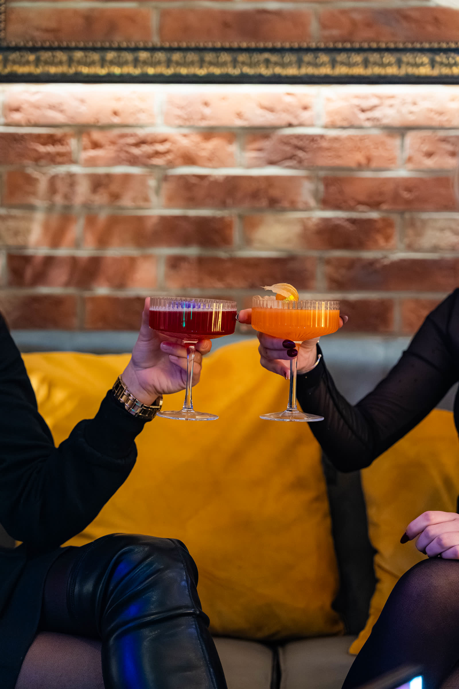 Hostia si štrngajú drinkami pred tehlovou stenou v bare Zlatý Dvor